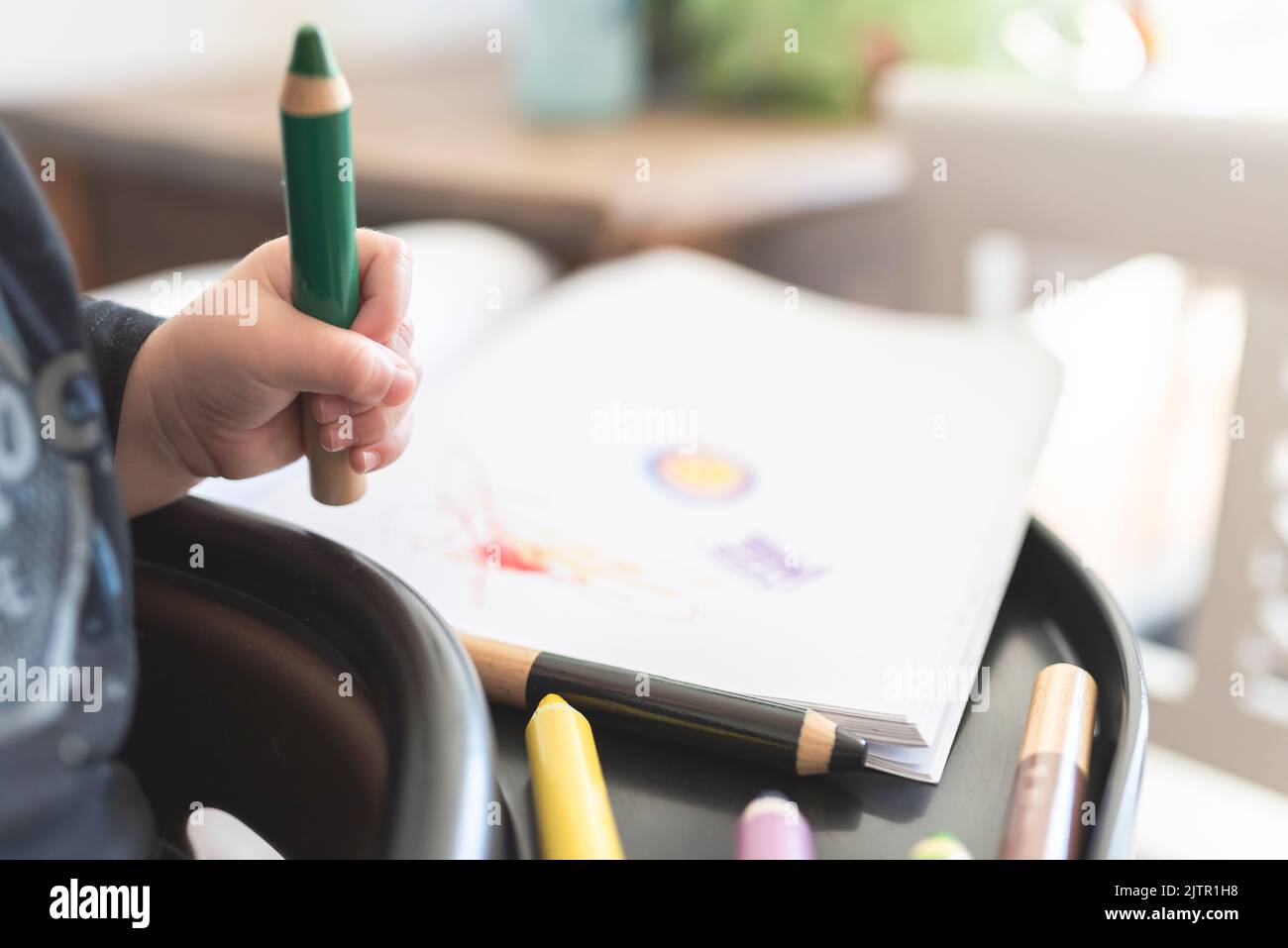 Nahaufnahme eines Kleinkindes mit Buntstiften, um ein Bild zu zeichnen Stockfoto