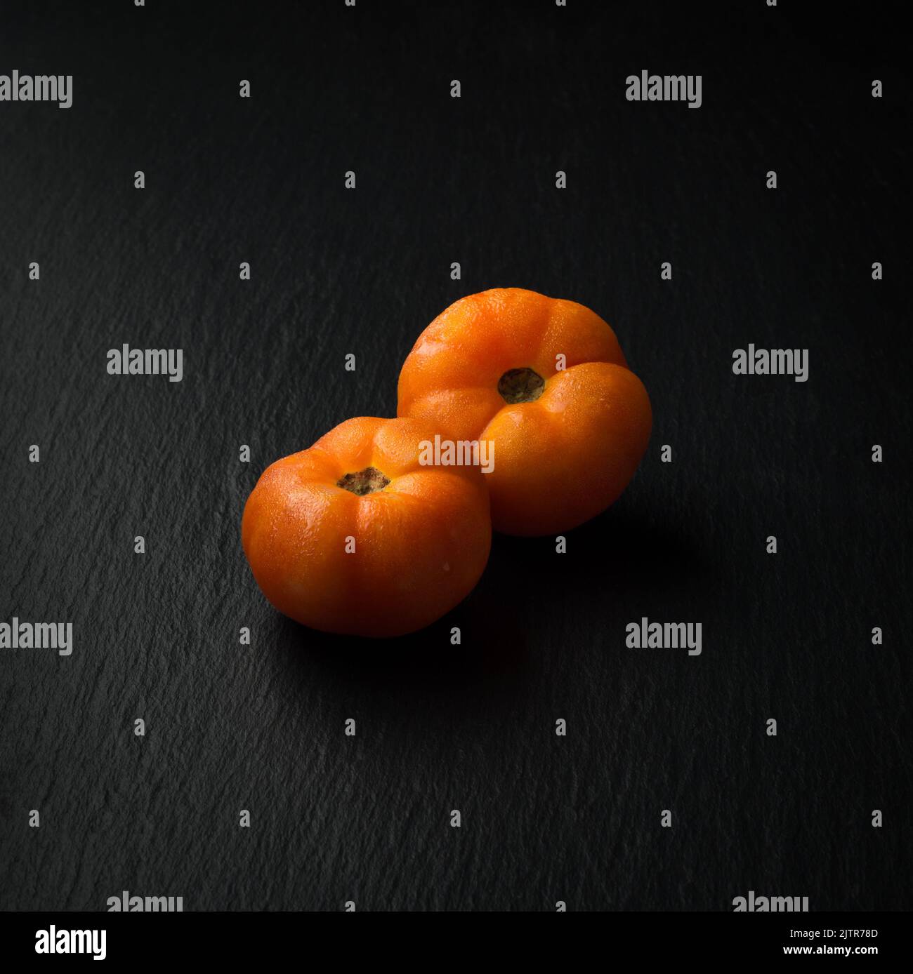 Frische Tomaten, essbare Beeren isoliert auf schieferschwarzer Oberfläche, Kopierraum Stockfoto