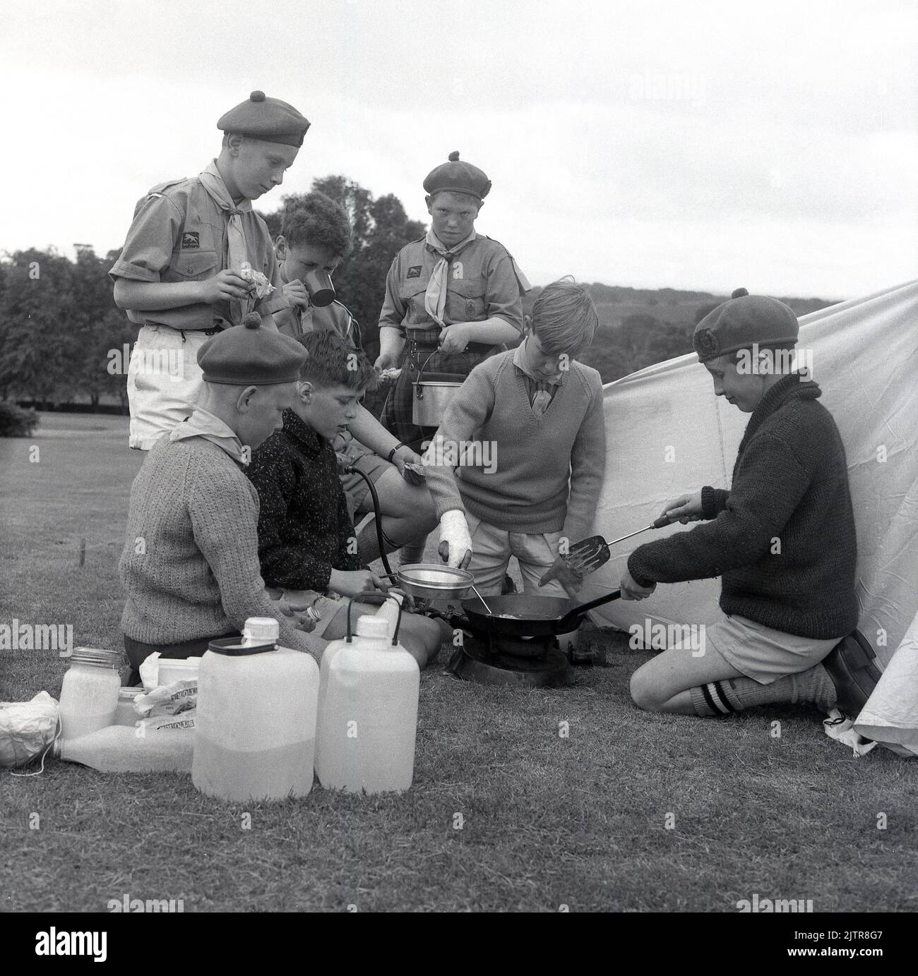 1965, historisch, Scouting in the Glen, Junge Scouts in Uniform und Barets, Kochen von Essen im Freien auf dem Gras vor einem Zelt, Schottland, Großbritannien, sieht aus wie Omelettes...... Stockfoto