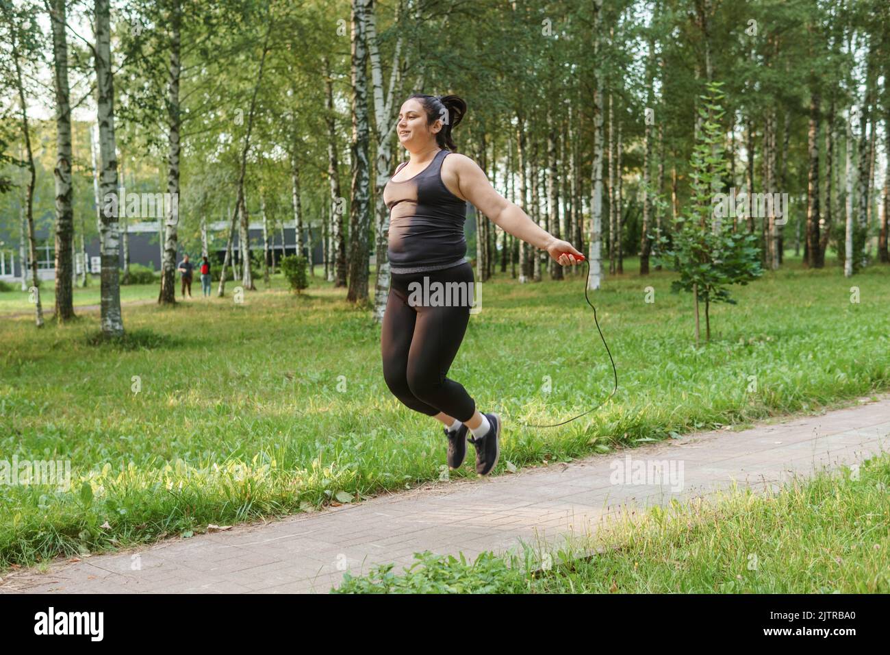 Eine charmante Brünette Frau plus-Größe Körper positiv praktiziert Sport in der Natur. Stockfoto