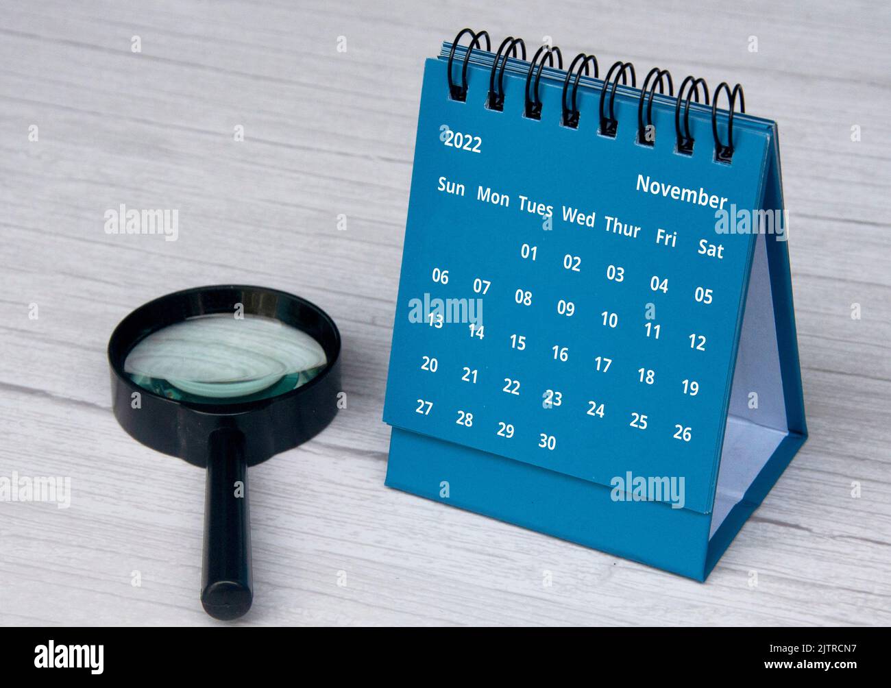 Juli 2022 blauer Tischkalender auf Holzschreibtisch mit Kopierraum und Lupe Stockfoto