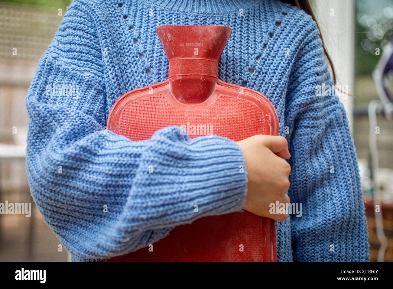 Kleines Mädchen hält heiße Wasserflasche gegen sie. Stockfoto