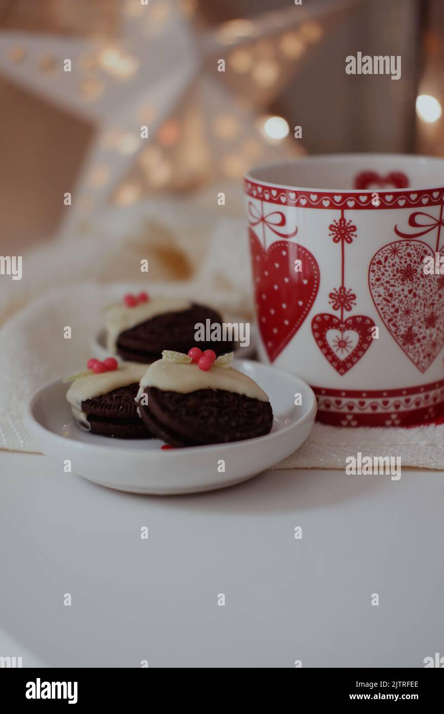 Schokoladenkekse in weiße Schokolade getaucht und mit Süßigkeiten/Süßigkeiten gekrönt, um kleine Weihnachts-Puddings zu kreieren. Stockfoto