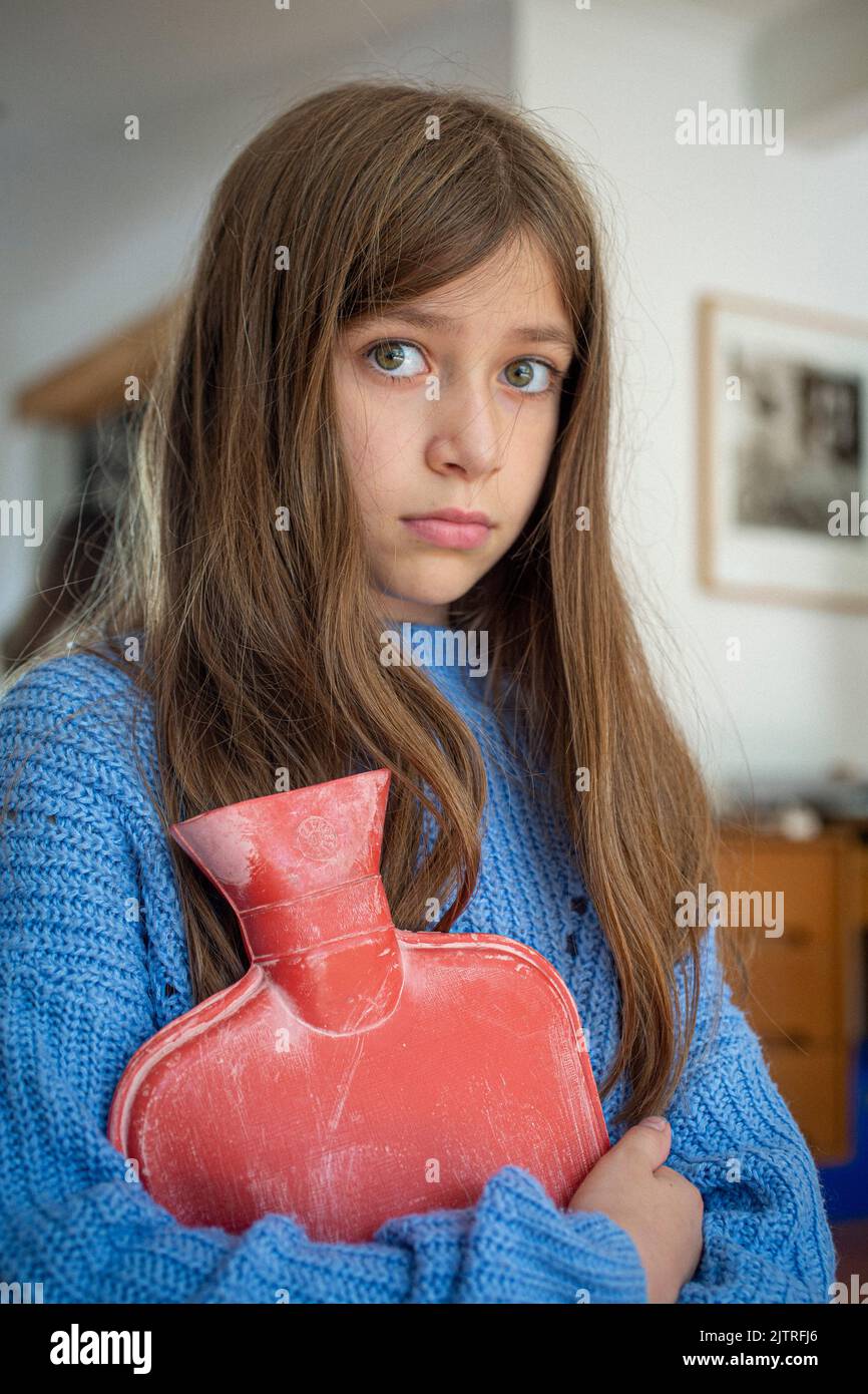 Kleines Mädchen hält heiße Wasserflasche gegen sie. Stockfoto