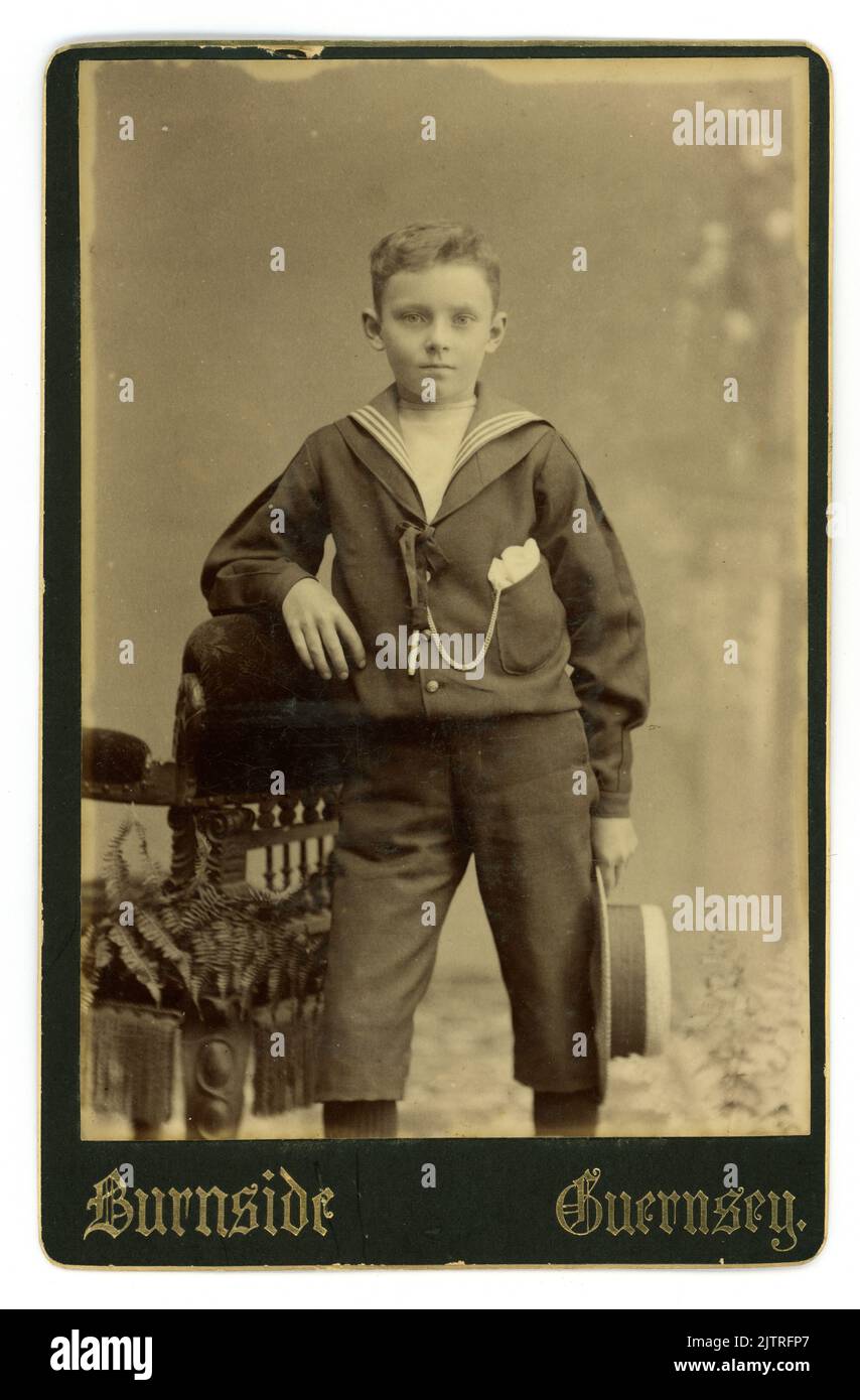 Originale viktorianische Studio-Porträtschrankkarte eines gut aussehenden jungen Jungen, etwa 8 oder 9 Jahre alt, der einen Seemann-Anzug trug, der zu dieser Zeit modisch war. Vom Studio James Burnside, St. Peter Port, Guernsey, Channel Isles. Um die 1890er Jahre Stockfoto