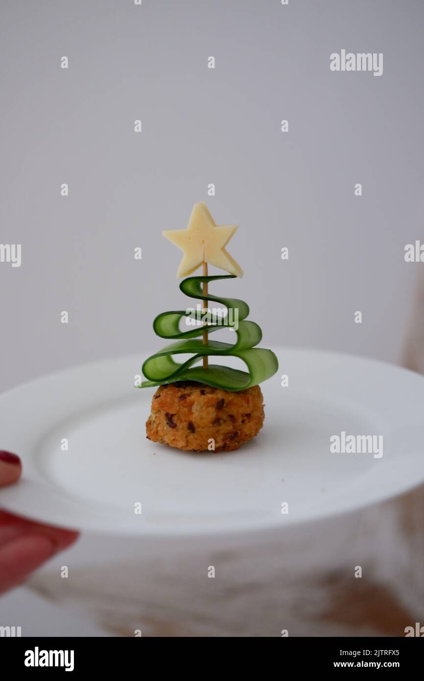 Eine Gurke, die wie ein Weihnachtsbaum auf einem Cocktailstab aussieht, der in ein Sandwich mit
