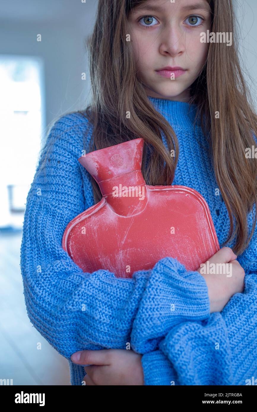 Kleines Mädchen hält heiße Wasserflasche gegen sie. Stockfoto