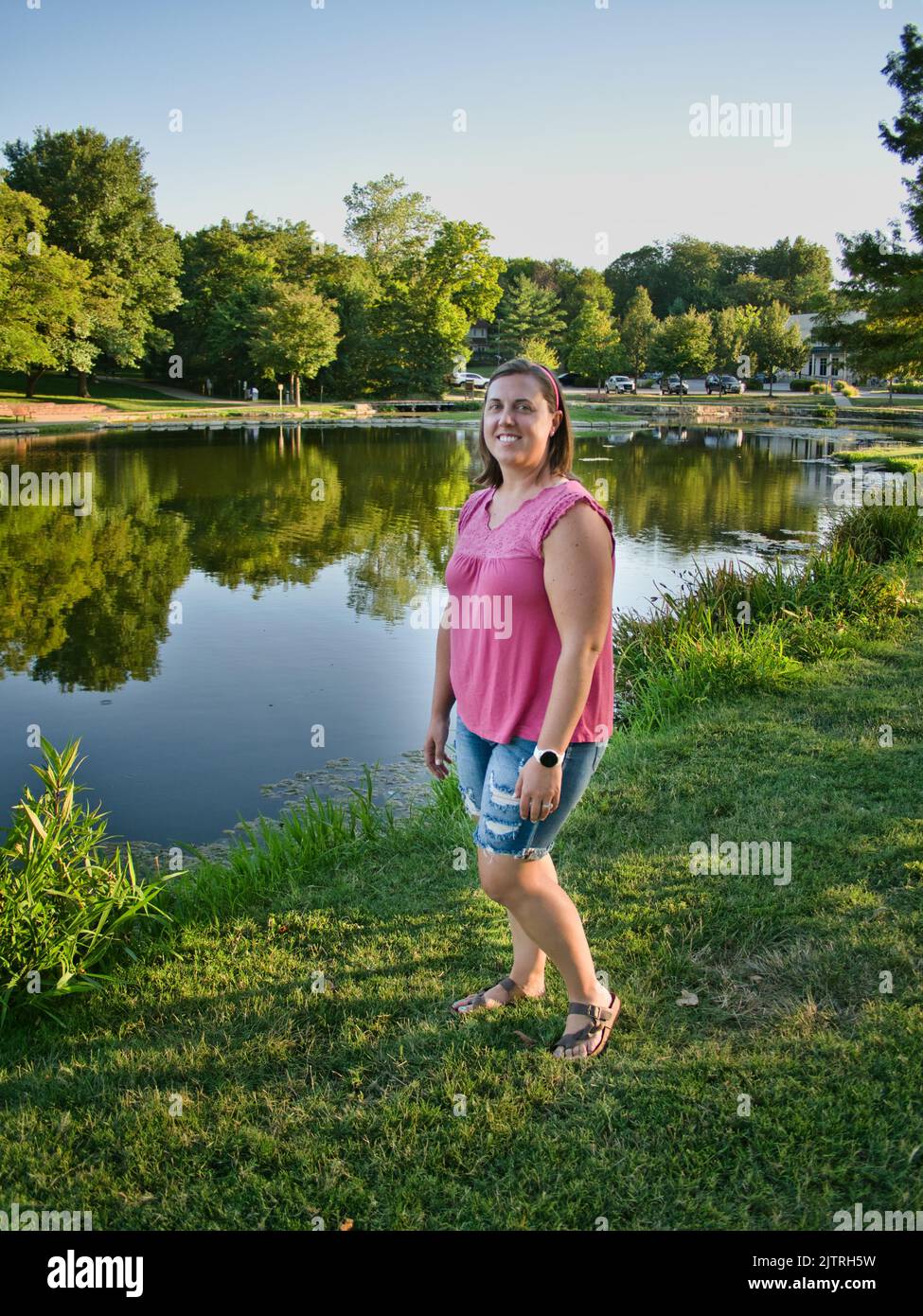 Brunette steht am reflektierenden Wasser des Sar Ko Par Park in Lenexa Kansas Stockfoto