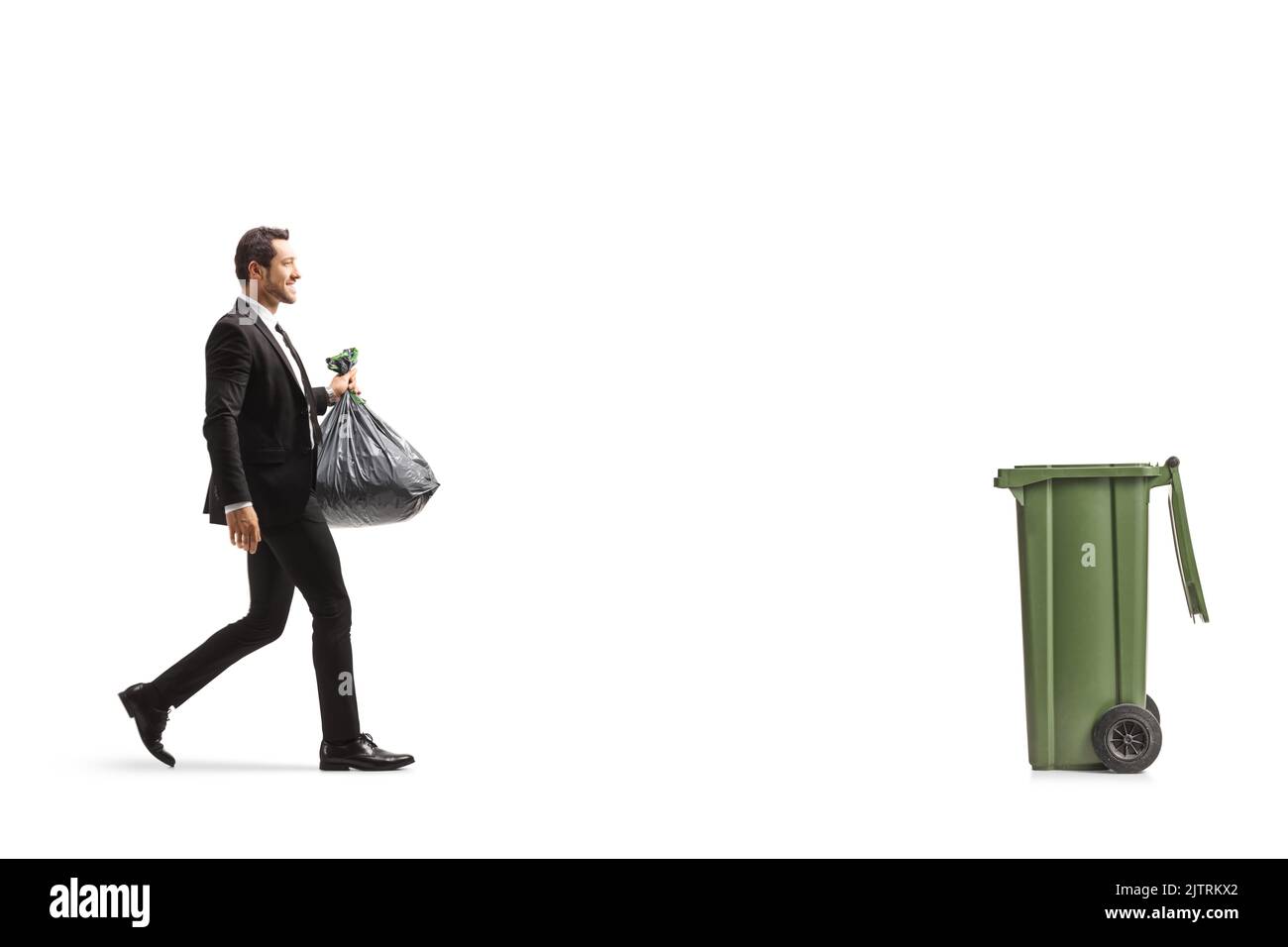Ganzkörperaufnahme eines Geschäftsmannes, der auf einen Behälter zugeht und einen Plastikmüll mit isoliertem Hintergrund trägt Stockfoto
