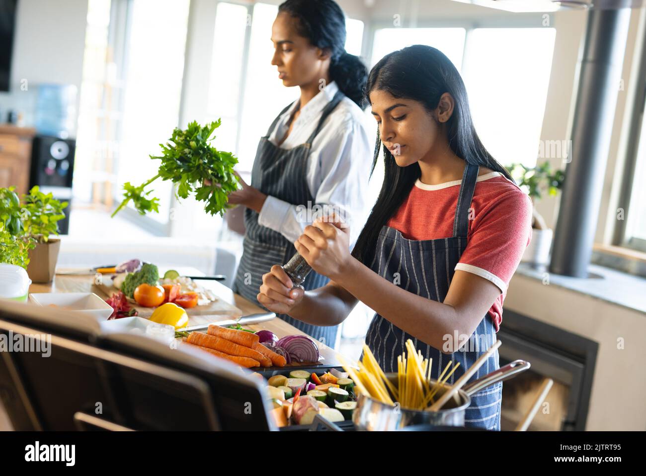 Biracial Mutter und Tochter tragen Schürzen und die Zubereitung von Essen in der Küche, Kopierer Platz Stockfoto