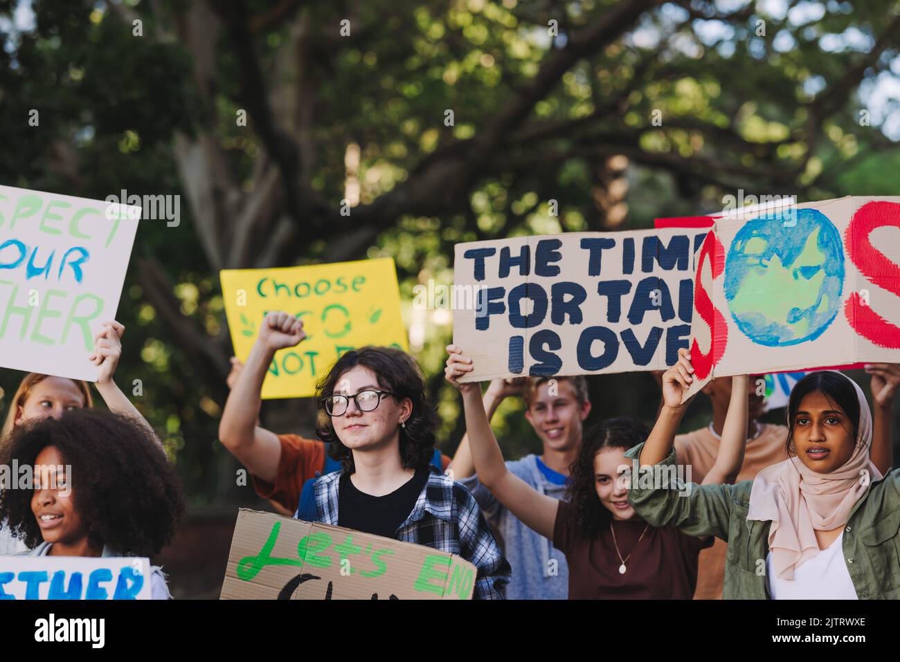 Auffällig, um den Planeten zu retten. Gruppe multikultureller Jugendaktivisten, die Plakate tragen, während sie gegen die globale Erwärmung und den Klimawandel marschieren. Vielfältig Stockfoto