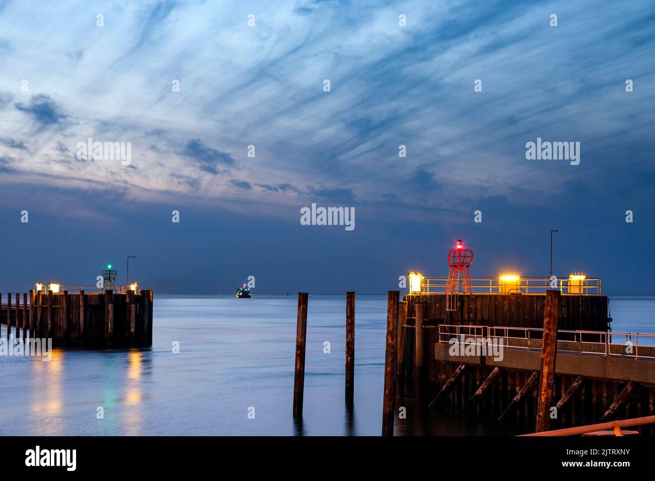Hafeneinfahrt in Cuxhaven an der Mündung der Elbe in der Nacht, auf dem Fairway ein Saugbagger während seiner Arbeit Stockfoto