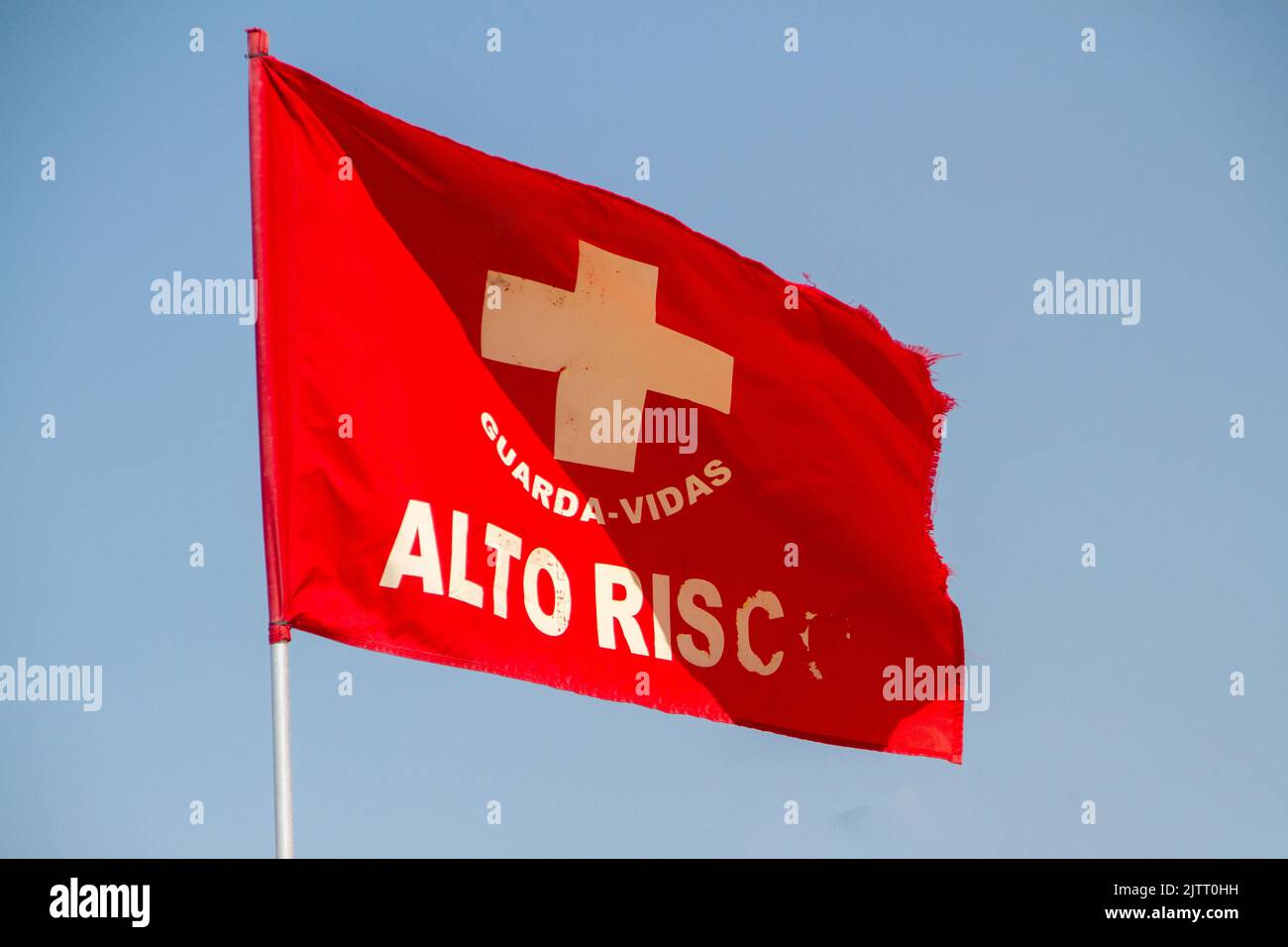 Rote Signalflagge auf portugiesisch „hohes Risiko“ am strand der küste von rio de janeiro, brasilien. Stockfoto