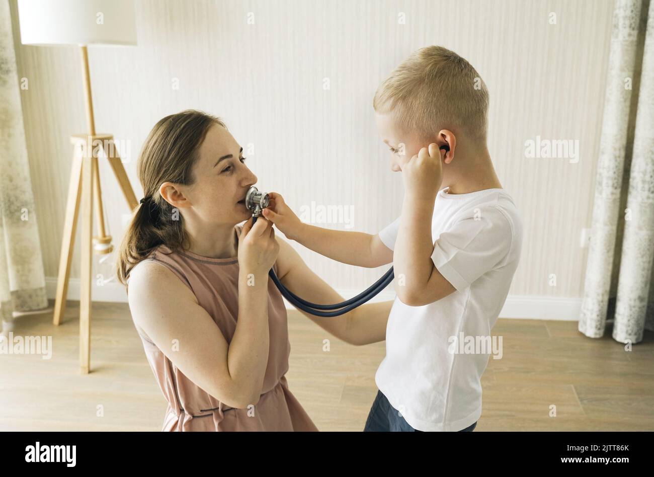 Der Junge hört durch ein Stethoskop, was seine Mutter ihm erzählt. Spiele für Kinder Stockfoto