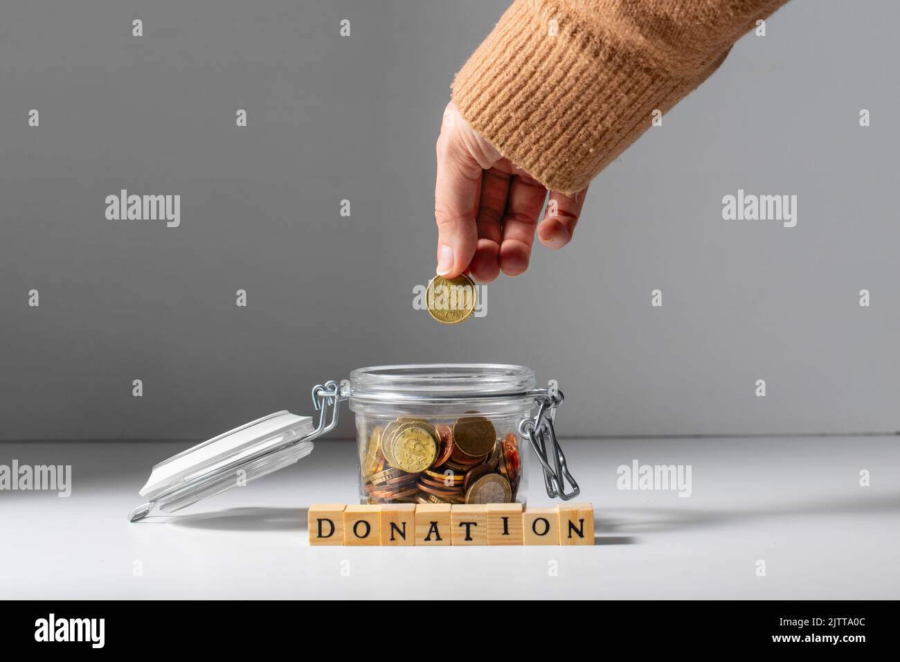 Hand legen Münze in Glas und Spenden Stockfoto