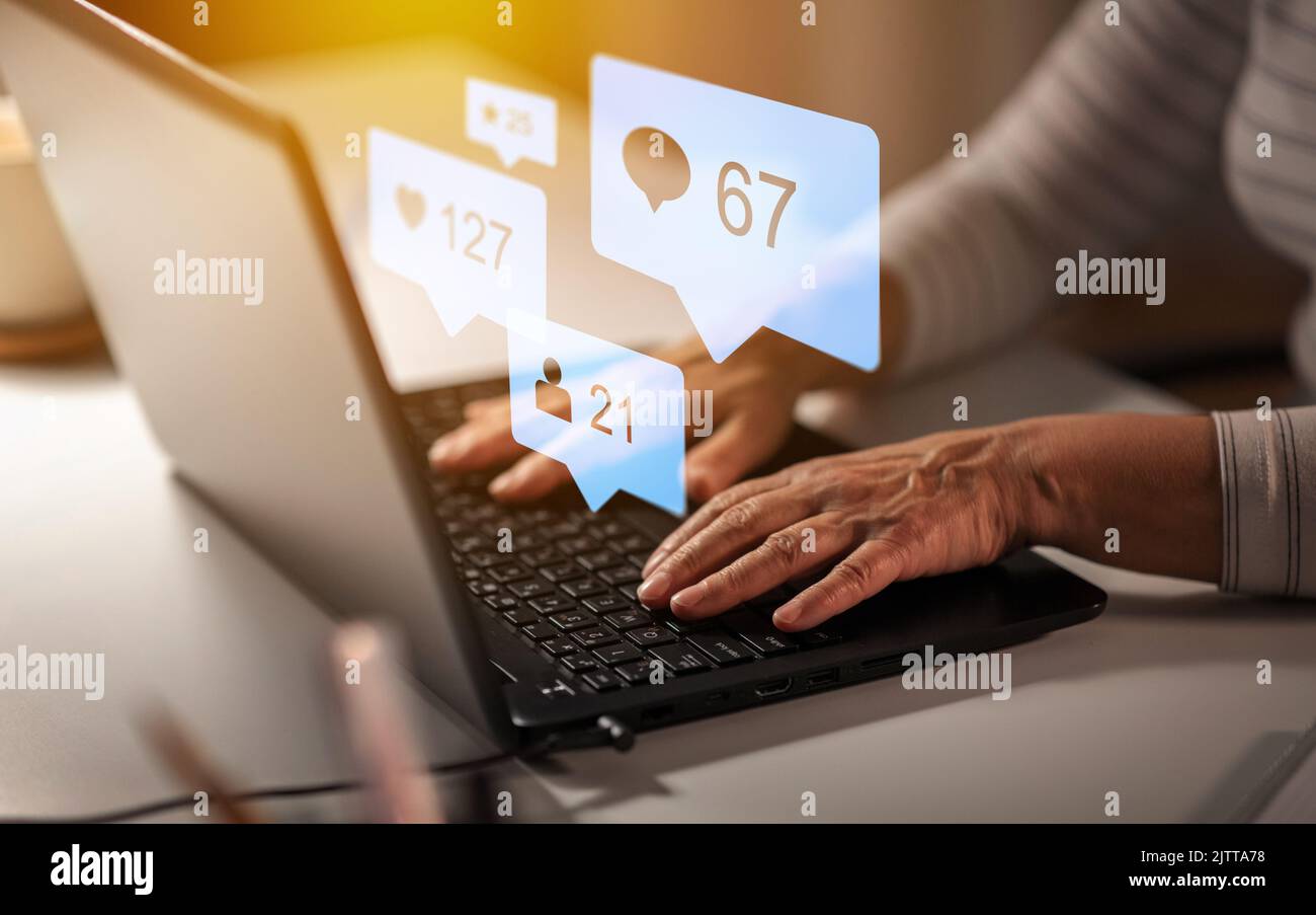 Hände einer alten Frau mit Laptop und Internet-Symbolen Stockfoto