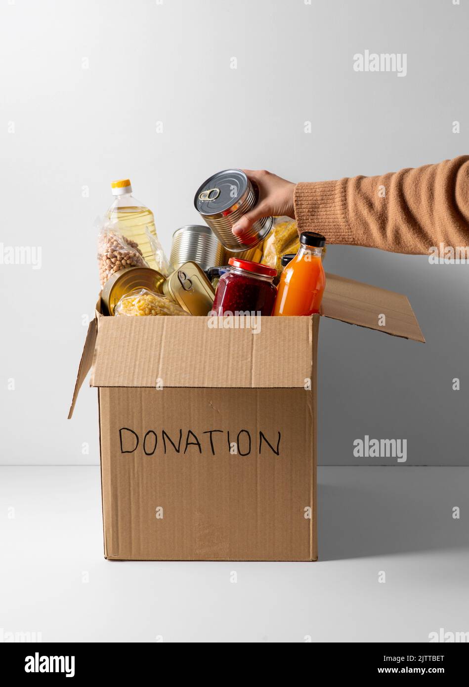 Nahaufnahme von Lebensmitteln in Spendenbox und Hand Stockfoto