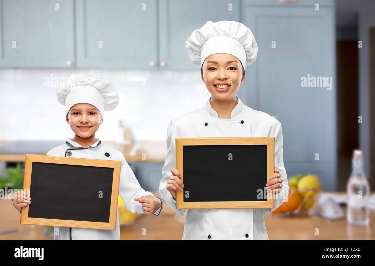Lächelnde Köchin und Mädchen mit Kreidetafeln Stockfoto