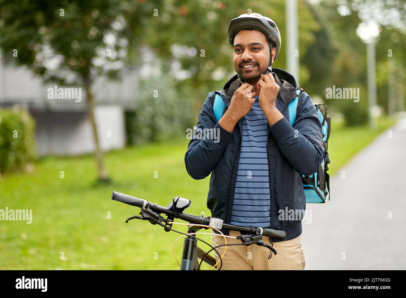 Lebensmittel Lieferung Mann Befestigung Fahrradhelm in der Stadt Stockfoto