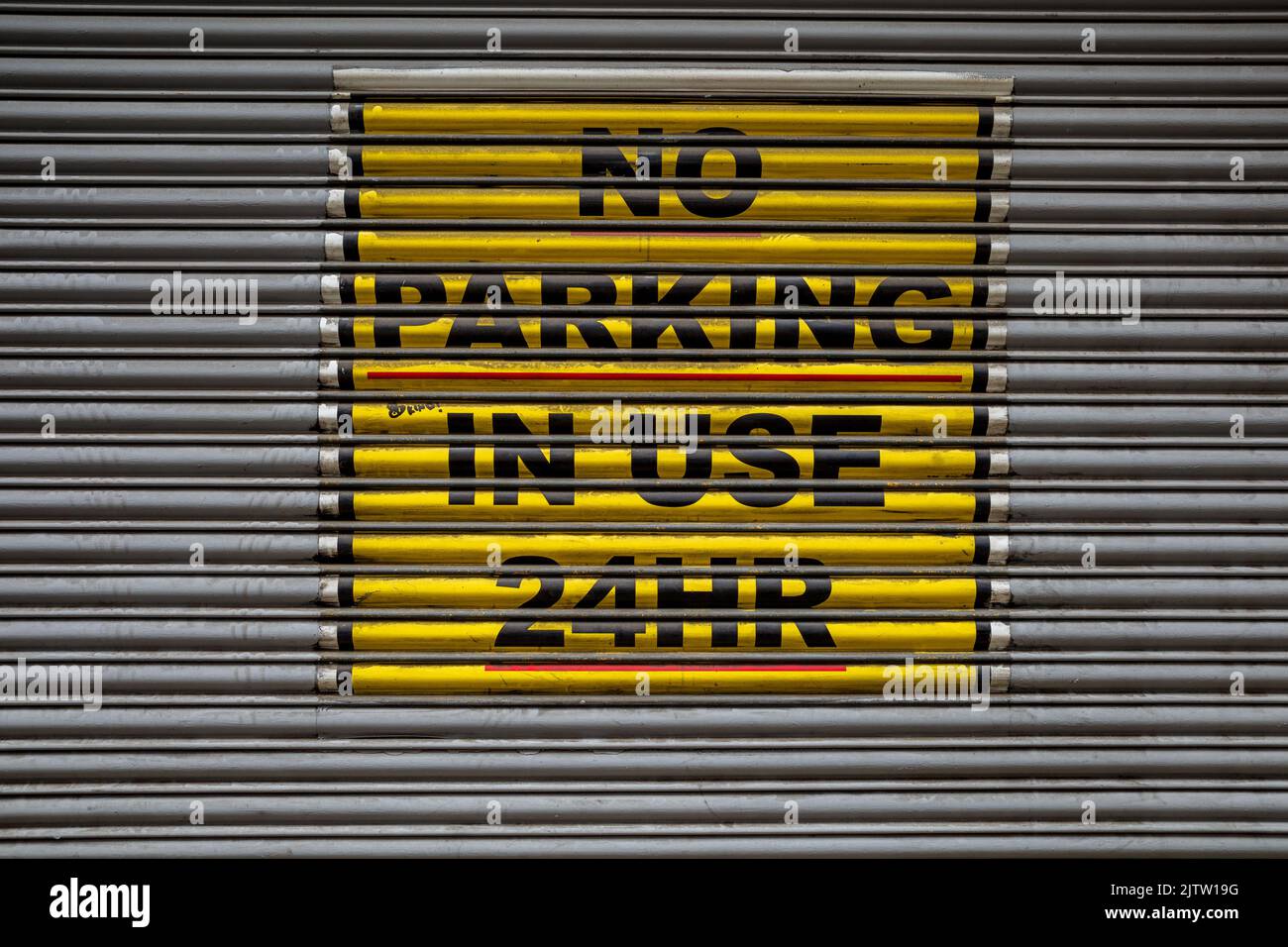 Kein Parkplatz in Benutzung 24hr Schild an einem Garagentor im Zentrum von London. No Parking in Use 24 HR Zeichen. Stockfoto