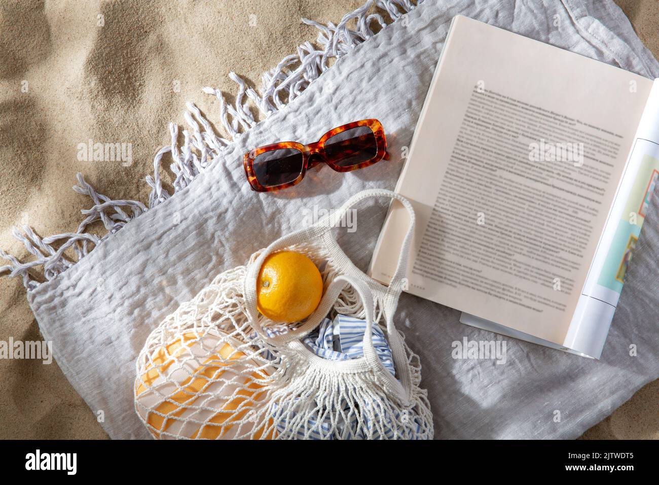 Beutel mit Orangen, Sonnenbrillen und Zeitschriften am Strand Stockfoto