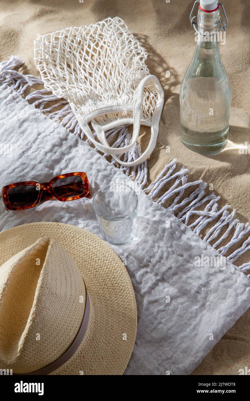 Sonnenbrille, Tasche, Flasche Wasser und Hut am Strand Stockfoto