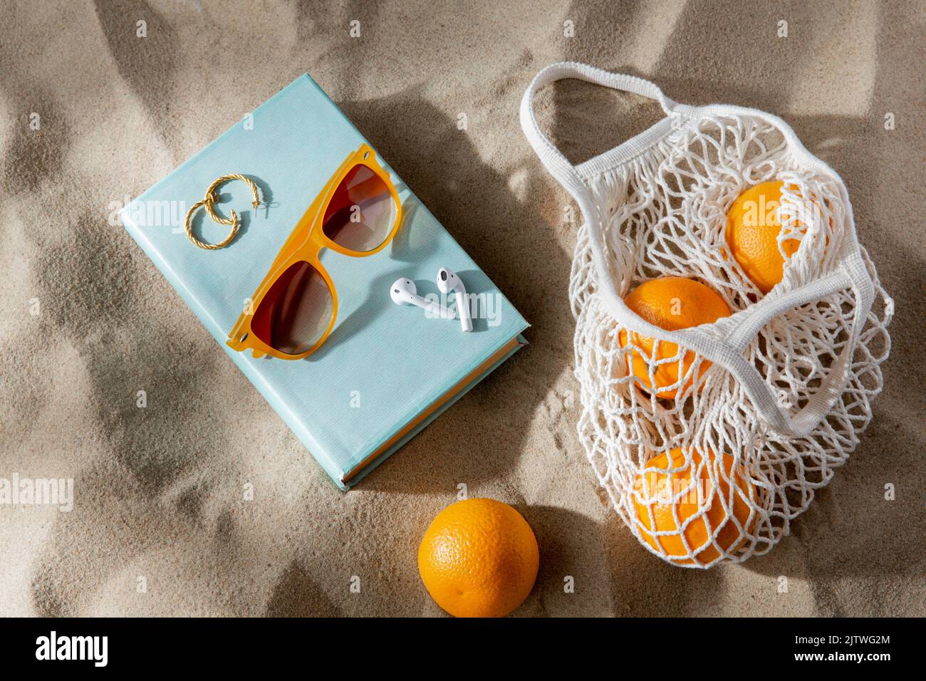 Beutel mit Orangen, Ohrstöpseln und Sonnenbrillen am Strand Stockfoto