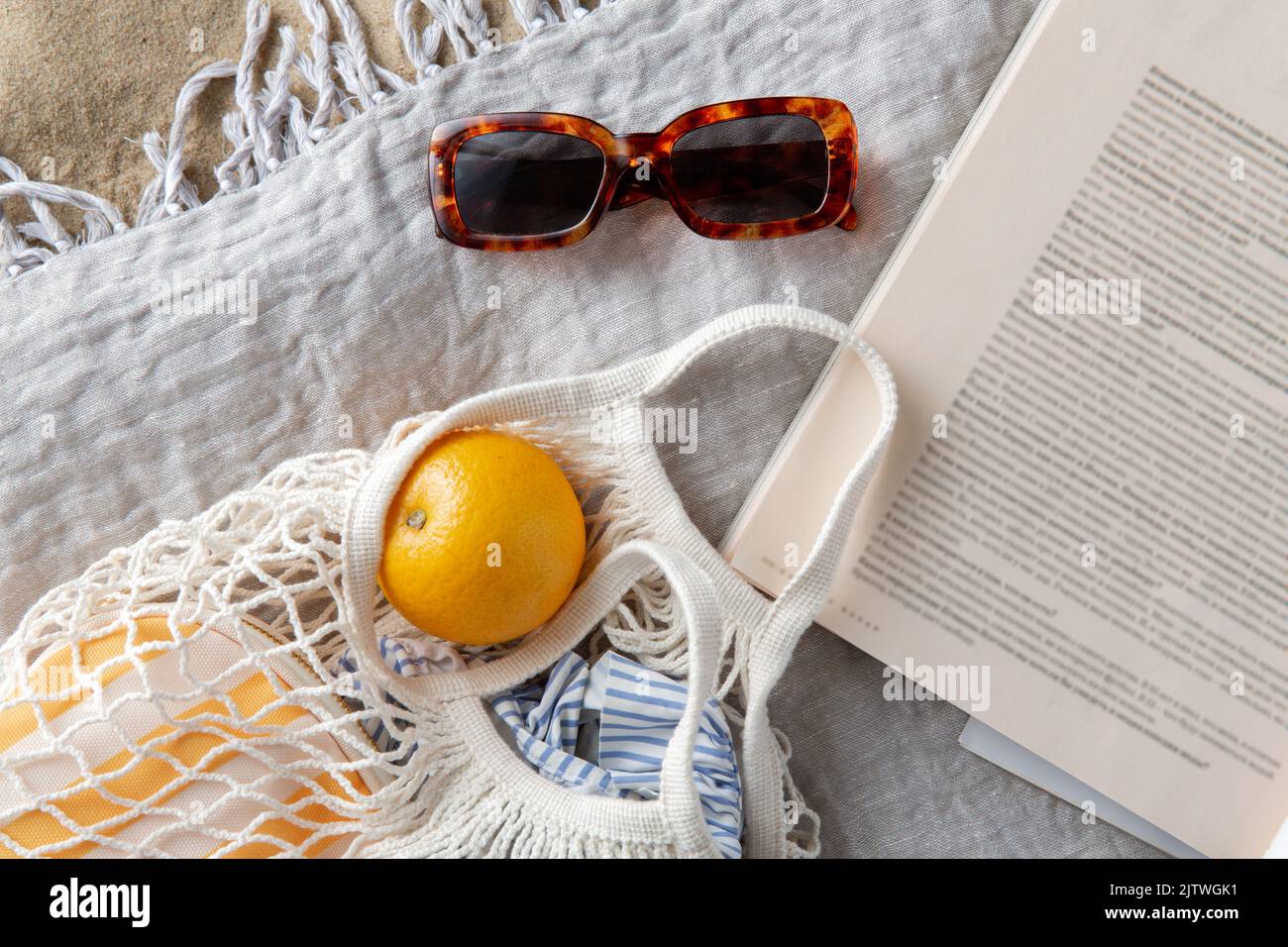 Beutel mit Orangen, Sonnenbrillen und Zeitschriften am Strand Stockfoto