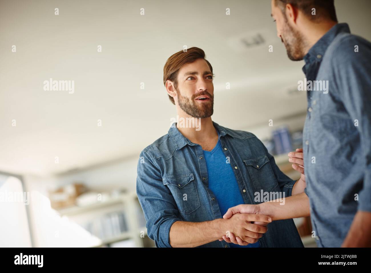 Ich denke, wir haben einen Deal: Zwei Geschäftsleute, die sich im Büro die Hände schütteln. Stockfoto