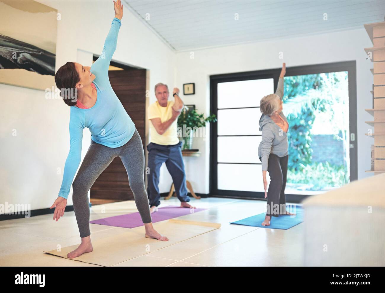 Sich gegenseitig motivieren, gesund zu bleiben. Ein Yoga-Lehrer führt ein Seniorenpaar in einem Yoga-Kurs. Stockfoto