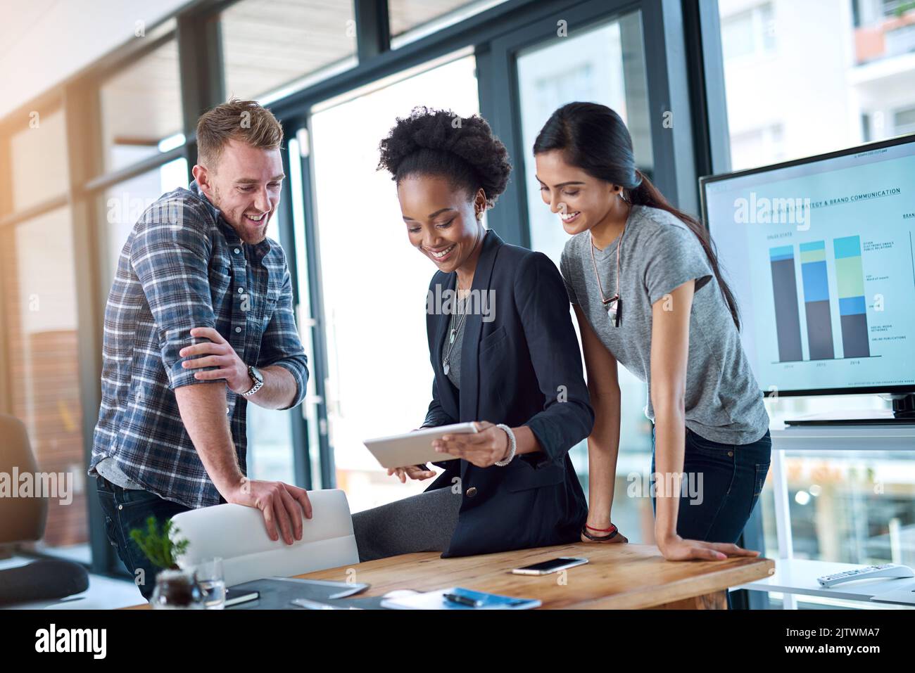 Teamwork kommt allen im Unternehmen zugute. Ein Team junger Kollegen nutzt bei der Arbeit gemeinsam ein digitales Tablet. Stockfoto