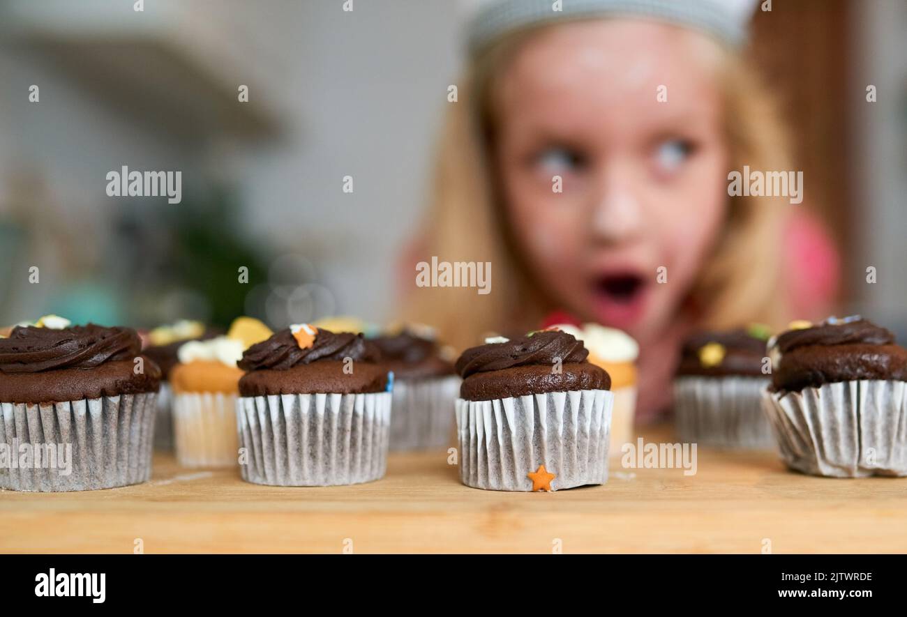 Ich kann nicht glauben, dass ich diese gemacht habe. Ein überrascht kleines Mädchen, das Cupcakes ansah, die sie zu Hause gebacken hat. Stockfoto