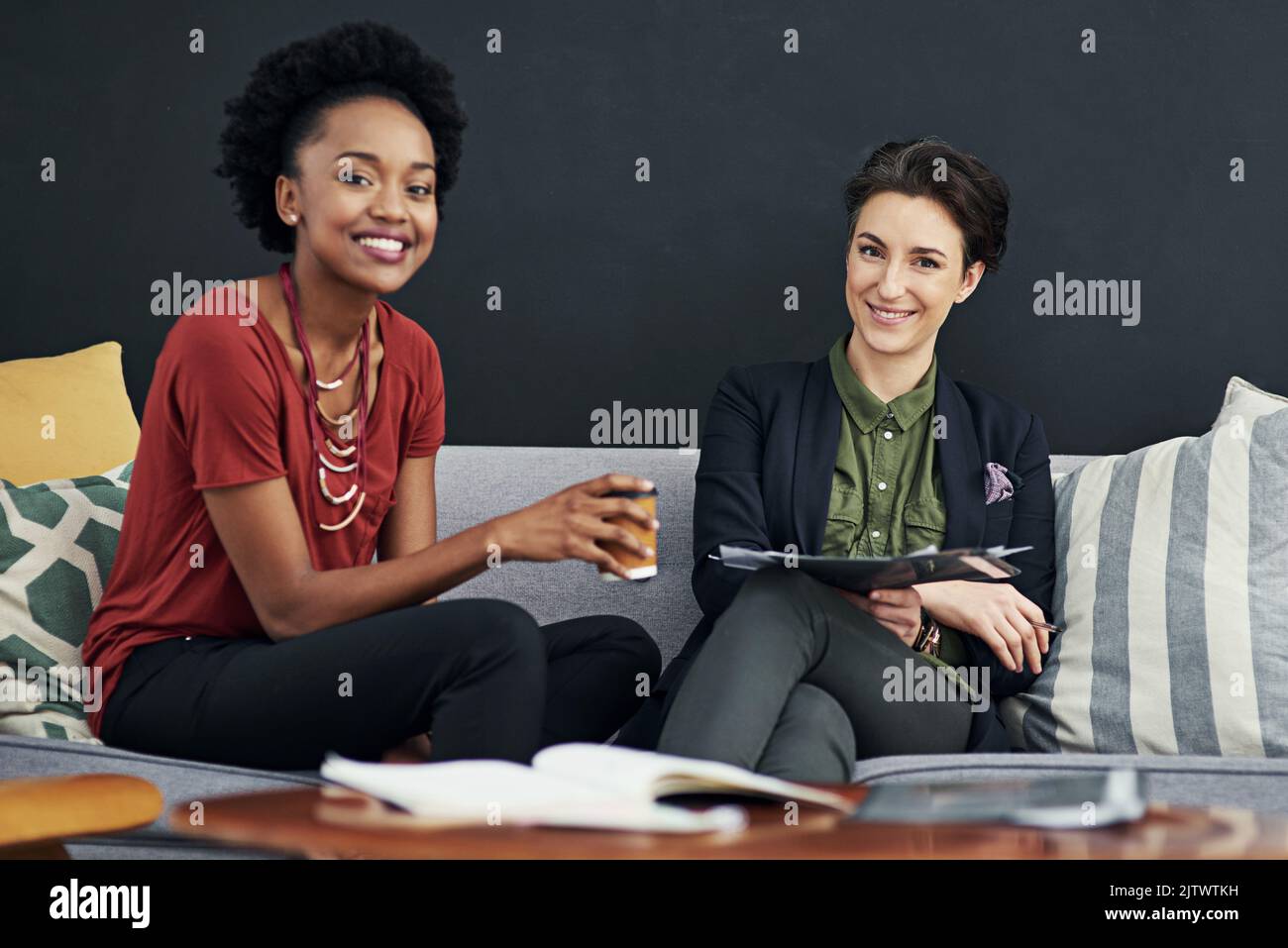 Wir brauchen keinen Sitzungssaal, um unsere Arbeit erledigen zu können. Ein Porträt von zwei Geschäftsfrauen, die sich spontan treffen, während sie in ihrem Büro auf einer Couch sitzen. Stockfoto