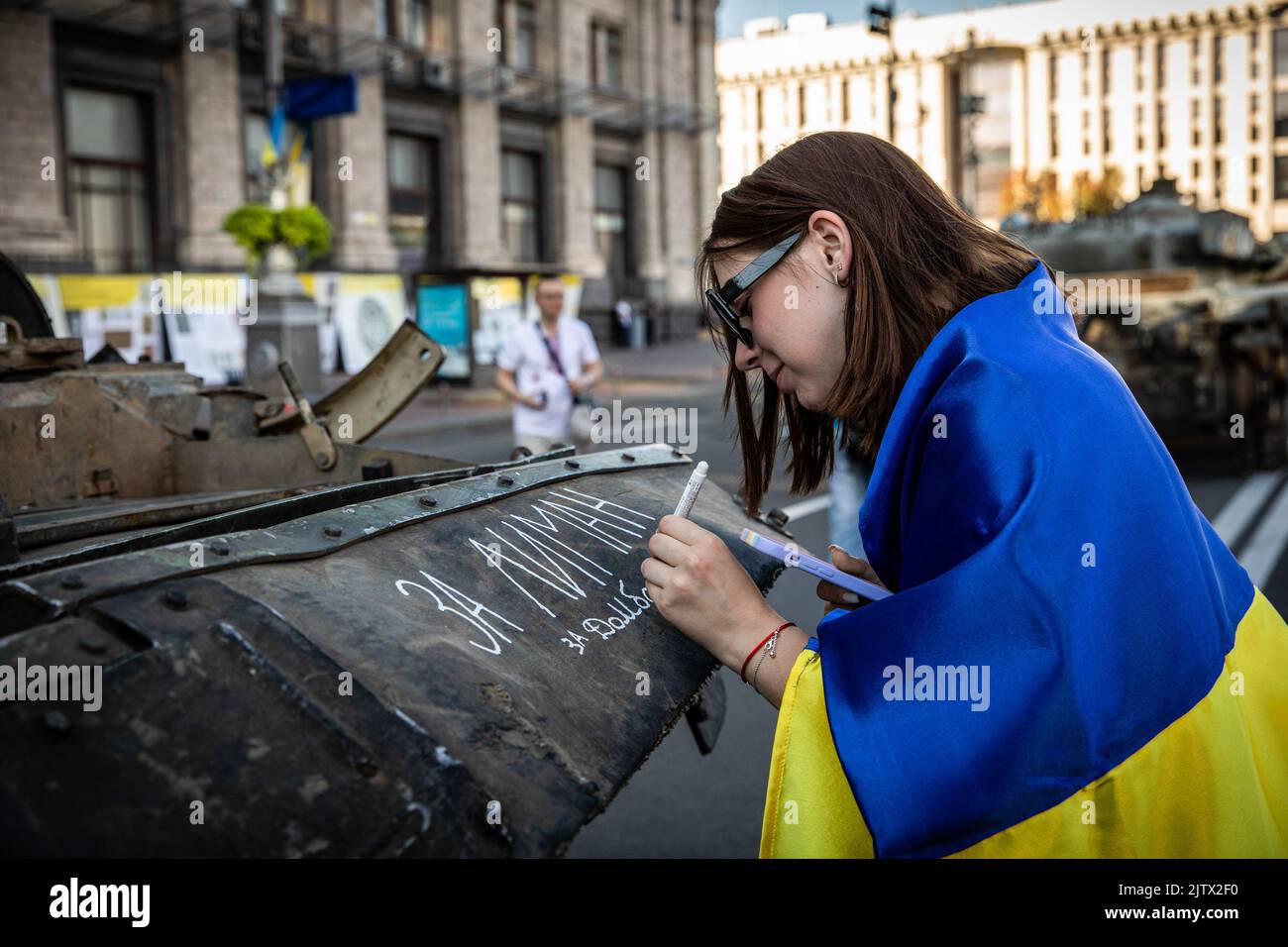 Kiew, Ukraine. 24. August 2022. Anya (18) aus Lyman schreibt der Donbas einen Slogan über einen abgerissenen russischen Panzer in Kiew, der am Unabhängigkeitstag der Ukraine stattfand. Und fast 6 Monate nach der umfassenden Invasion der Ukraine am 24. Februar hält die Hauptstadt Kiew in der Hauptstraße der Chreschajtk-Straße eine Ausstellung ab, in der mehrere zerstörte militärische Ausrüstungen, Panzer und Waffen der Streitkräfte der Russischen Föderation (AFRF) gezeigt werden. (Foto von Alex Chan Tsz Yuk/SOPA Images/Sipa USA) Quelle: SIPA USA/Alamy Live News Stockfoto