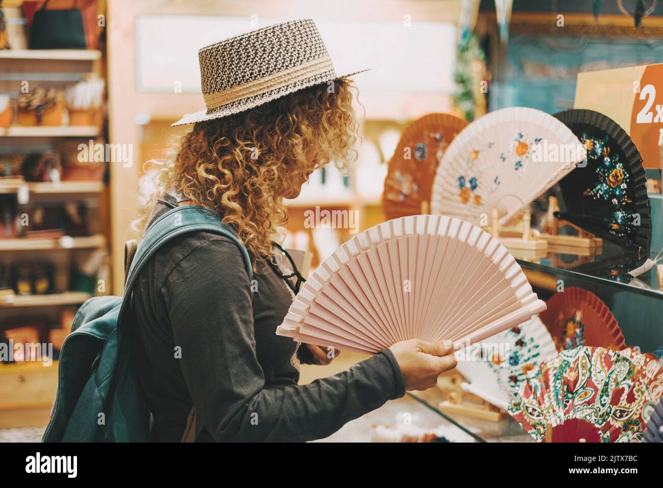 Eine Frau, die in einem Geschäft in der Freizeit einkaufen geht, berührt faltbare Ventilatoren für Hitze und Klimawandel. Konzept von Stockfoto