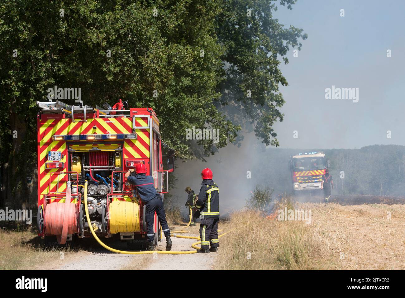 Feuerwehrleute, die ein Stoppelfeuer auf einem bereits geernteten Feld, Departement Eure-et-Loir, Region Centre-Val-de-Loire, Frankreich, Europa, löschen. Stockfoto