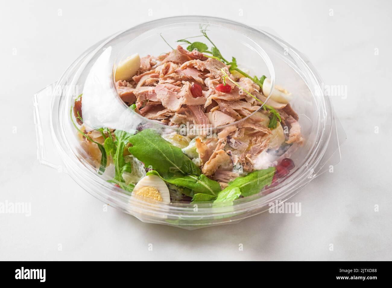 Plastikpaket mit gesund gebackenem Schinkensalat zum Mitnehmen oder zur Lebensmittelzustellung auf weißem Hintergrund. Essen in der Lunchbox. Nahaufnahme Stockfoto