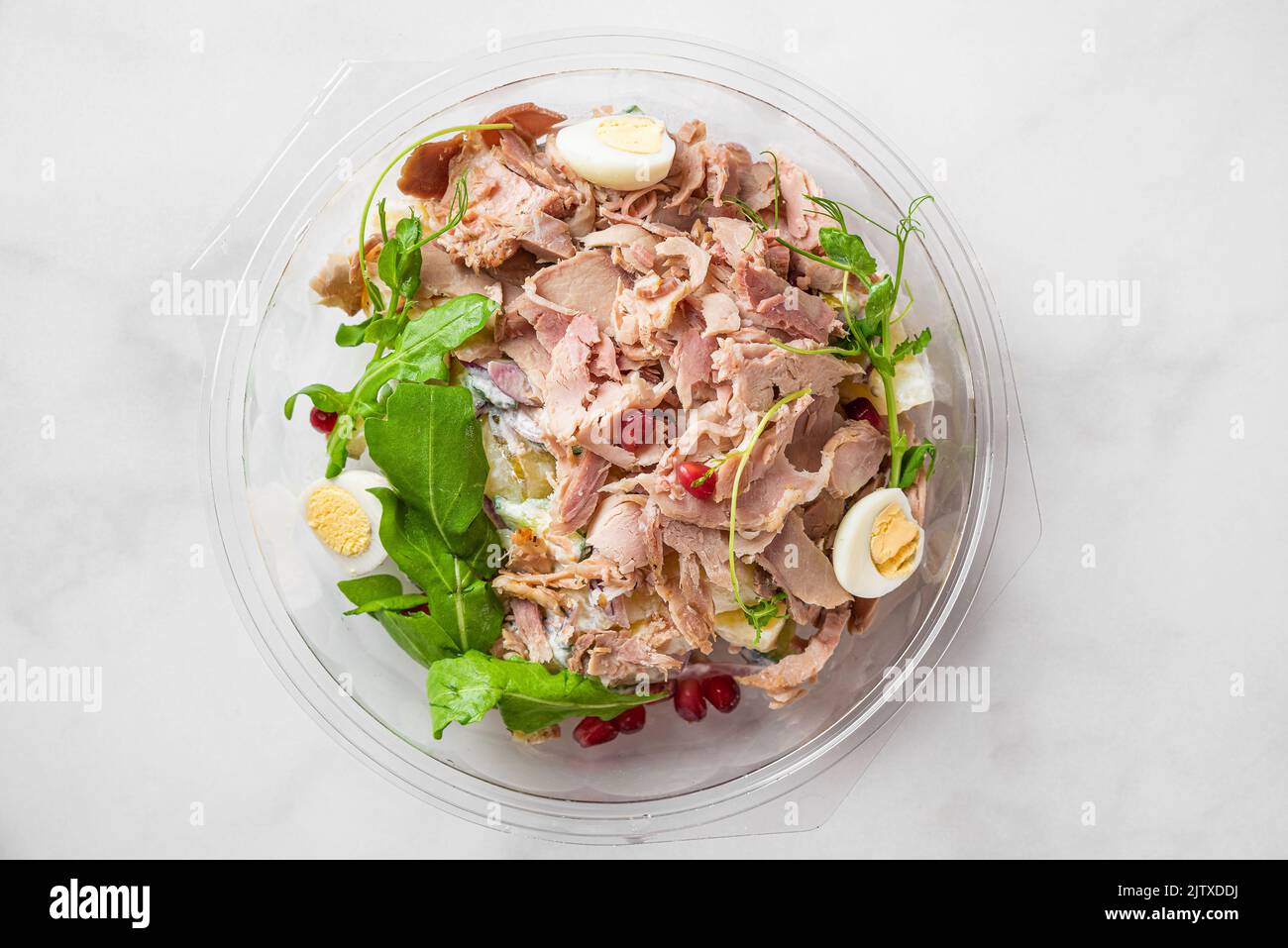 Gesund gebackener Schinkensalat mit Rucola, Kartoffeln, Eiern, Granatapfel in Plastikverpackung zum Mitnehmen. Essen in der Lunchbox. Draufsicht Stockfoto