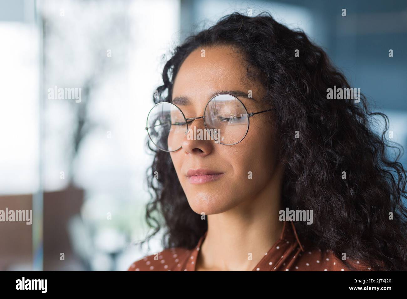 Nahaufnahme Porträt Programmierer-Ingenieurin-Entwickler mit geschlossenen Augen in der Brille, träumen und visualisieren gewünschte Ergebnis, Geschäftsfrau arbeitet in modernen Büro, Hispanic mit lockigem Haar in casual Stockfoto