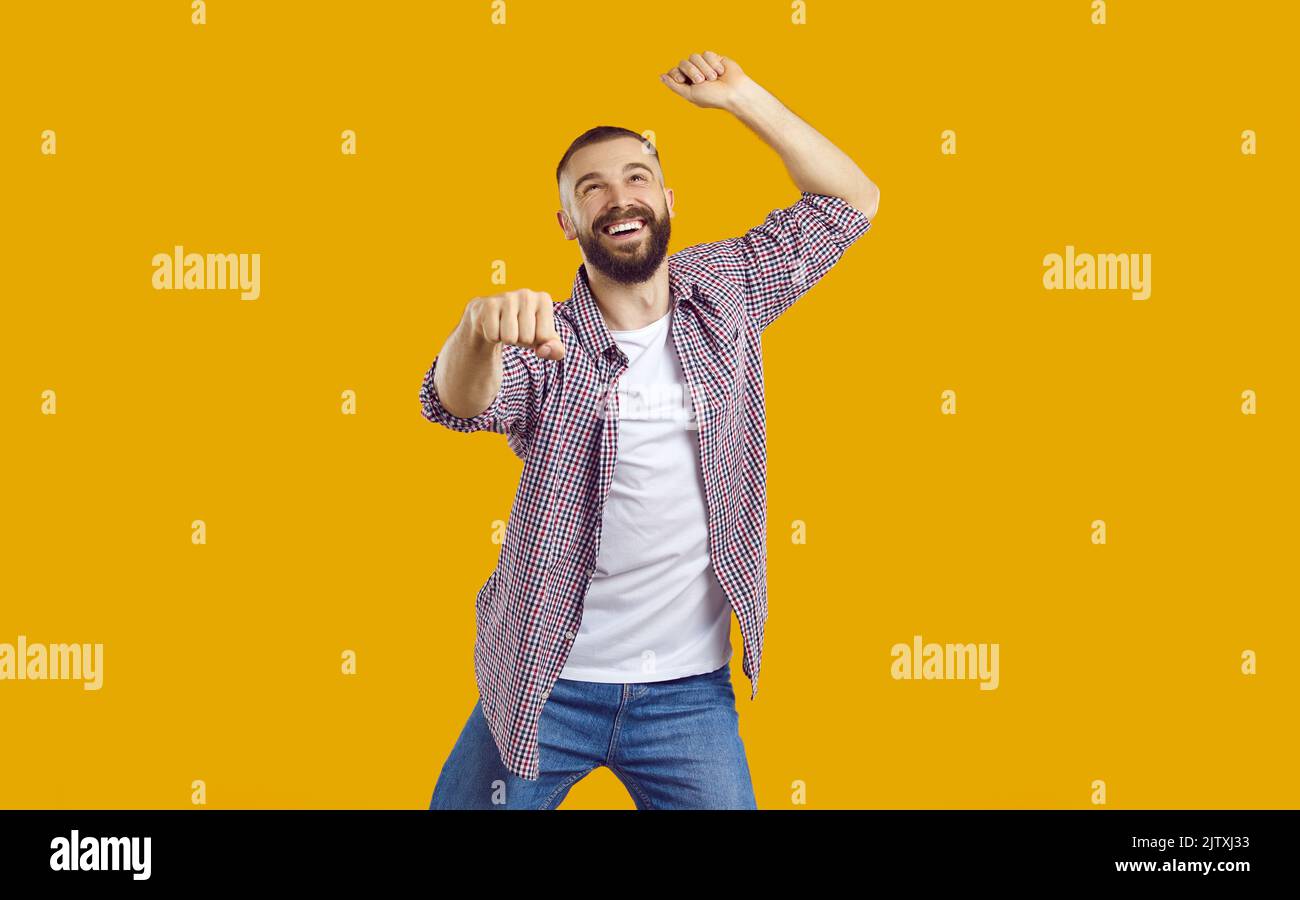 Fröhlicher Mann in lässiger Kleidung, der im gangnam-Stil auf einem orangegelben Hintergrund tanzt Stockfoto