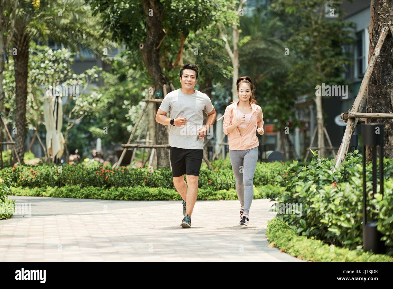 Fröhliches junges vietnamesisches Paar, das im Park läuft Stockfoto