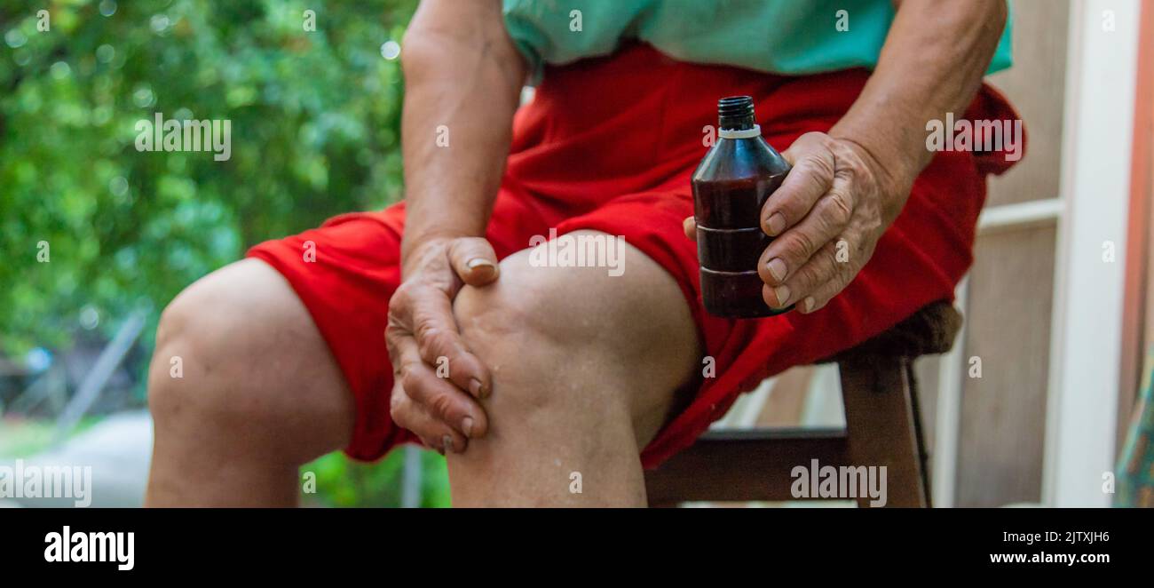 Großmutter behandelt ihre Knie, schmiert die Medizin. Selektiver Fokus. Stockfoto