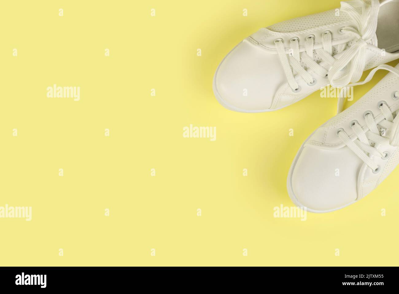 Weiße weibliche Sneakers auf gelbem Hintergrund mit Kopierraum. Draufsicht, flach liegend. Mode-Mockup Stockfoto