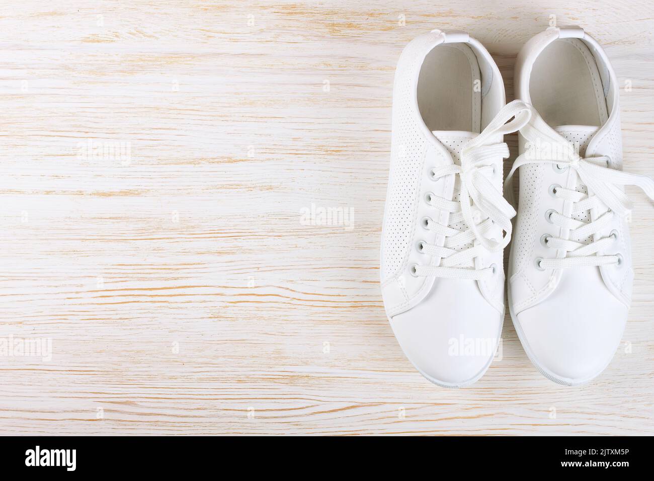 Weiße weibliche Sneakers auf weißem Holzhintergrund mit Kopierraum. Draufsicht, flach liegend. Stockfoto