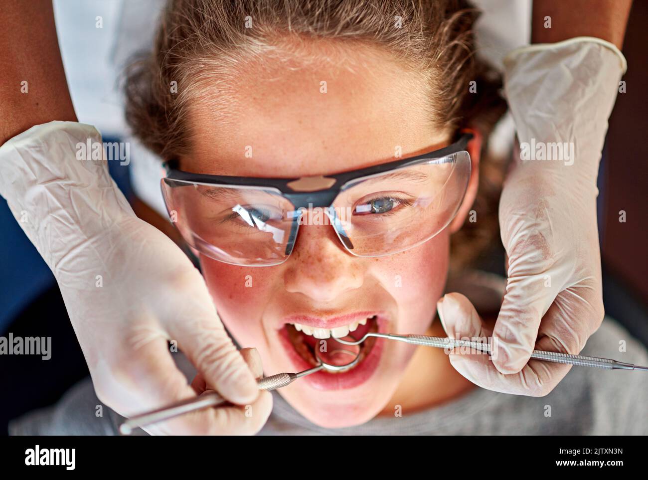 Kommt her. Hochwinkelige Aufnahme eines jungen Mädchens, das ihre Zähne von einem Zahnarzt untersuchen ließ. Stockfoto