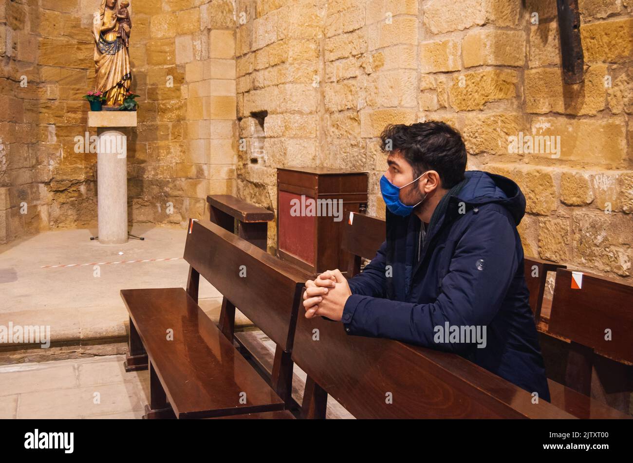 Kleiner Junge mit einer Maske, der im Kloster San Pedro el Viejo, Huesca, betet. Stockfoto