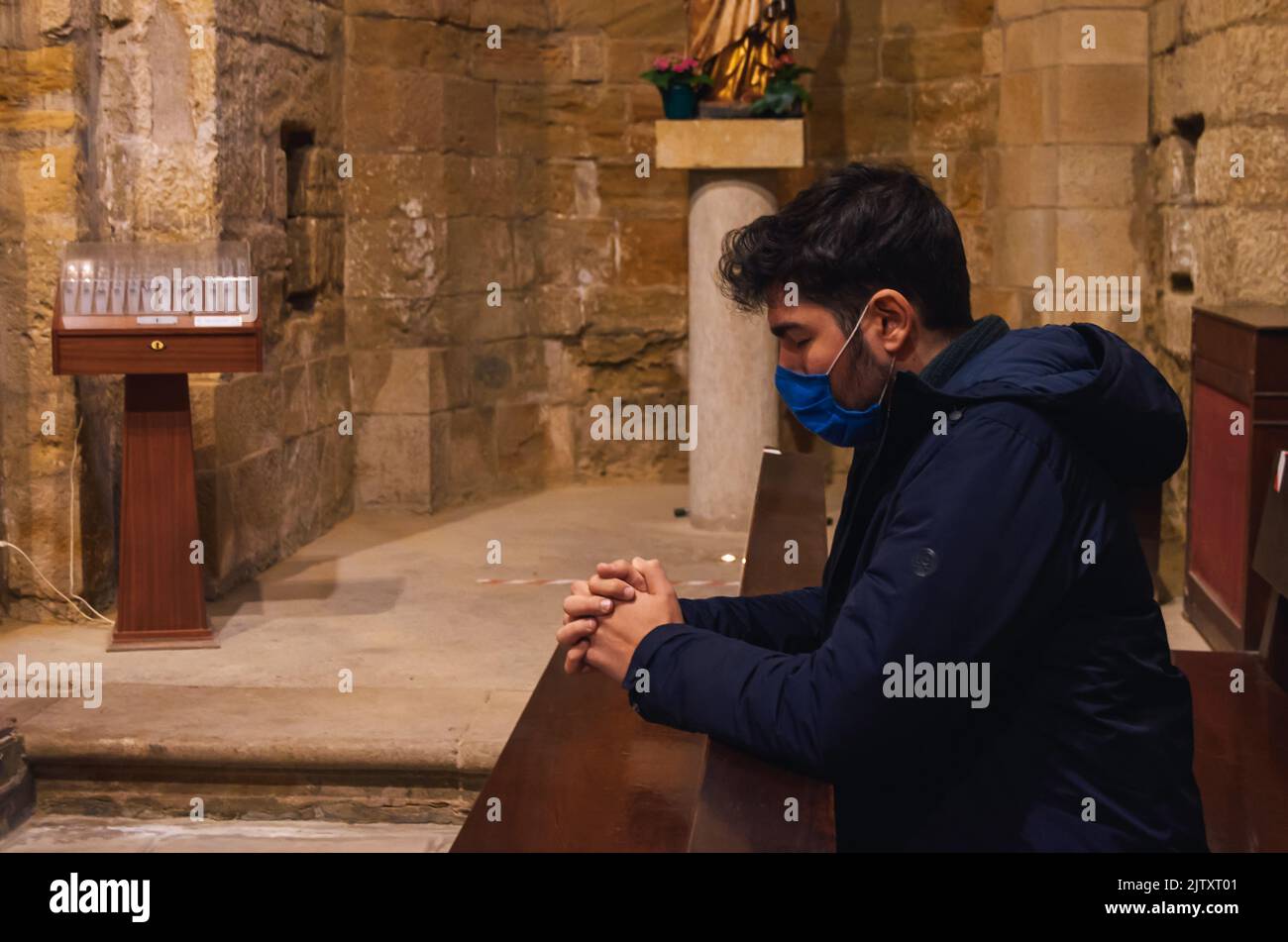 Kleiner Junge mit einer Maske, der im Kloster San Pedro el Viejo, Huesca, betet. Stockfoto