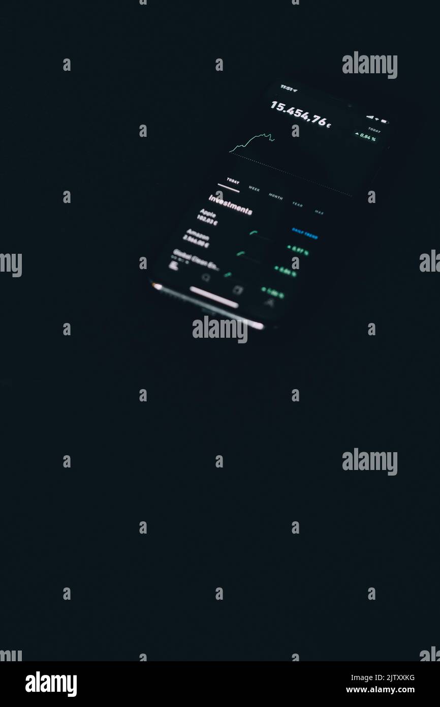 Eine vertikale Infografik der Investitionen auf einem Telefonbildschirm, umgeben von totaler Dunkelheit Stockfoto