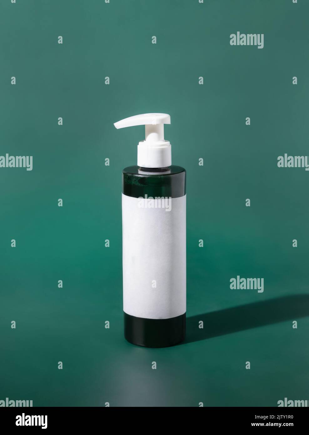 Eine nachfüllbare Kunststoffflasche mit einer Pumpe und leerem Etikett auf grünem Nahaufnahme. Verpackungsmockup. Hautpflegeprodukt, Gesichtsreiniger oder Lotion. Natürlich Stockfoto