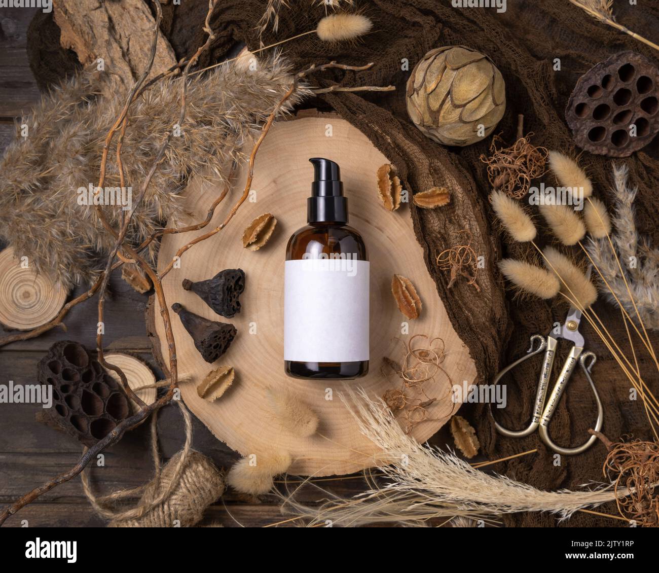 Glas eine Pumpflasche auf Holz in der Nähe von natürlichen Boho Dekorationen Draufsicht, Label Mockup. Hautpflegeprodukt, Lotion oder Essenz. Böhmische Umweltfreundlichkeit Stockfoto